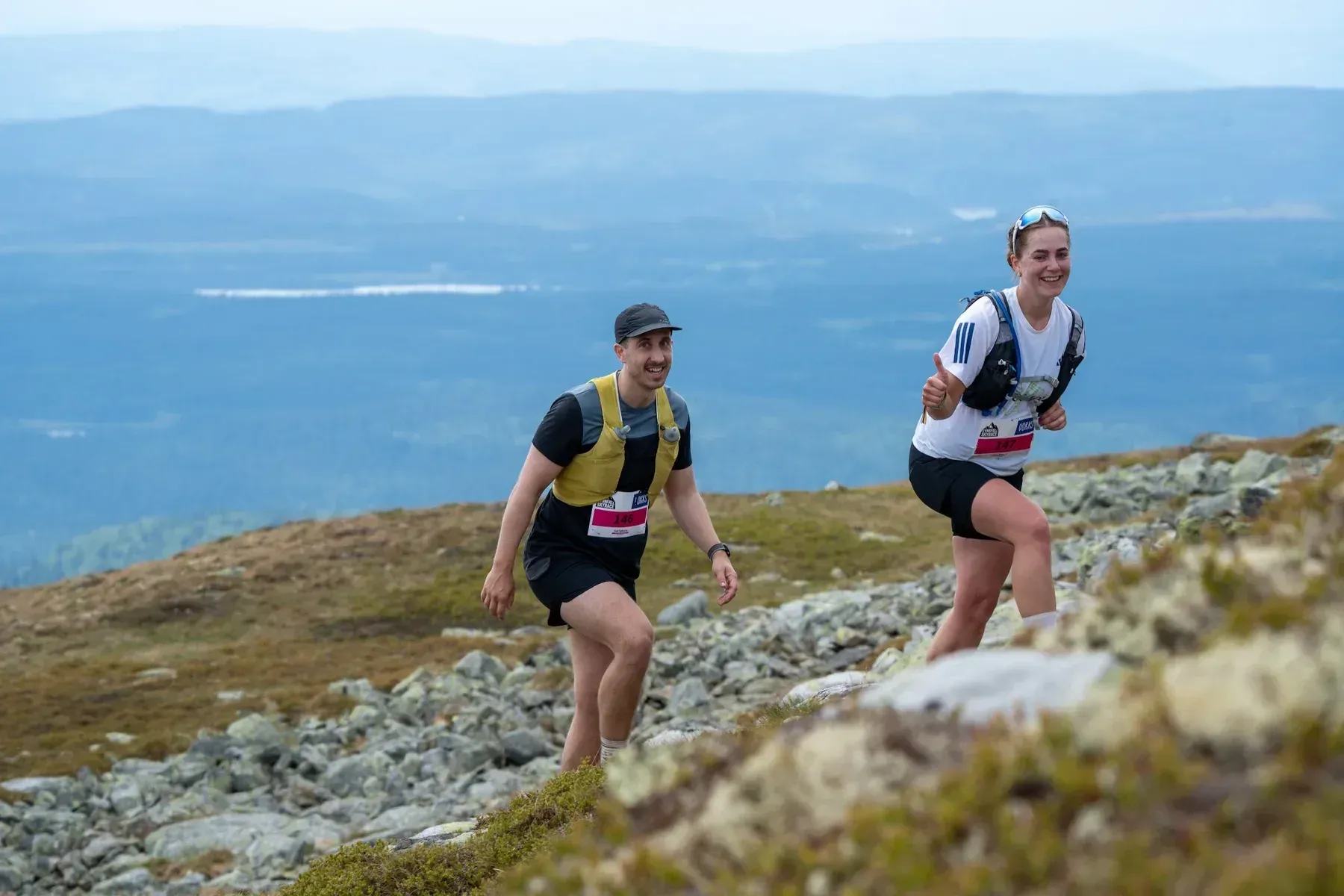 To løpere side om side i steinete fjellterreng